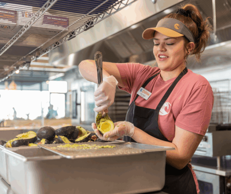 Costa Vida employee scooping ripe avocados to make fresh guacamole in the kitchen.