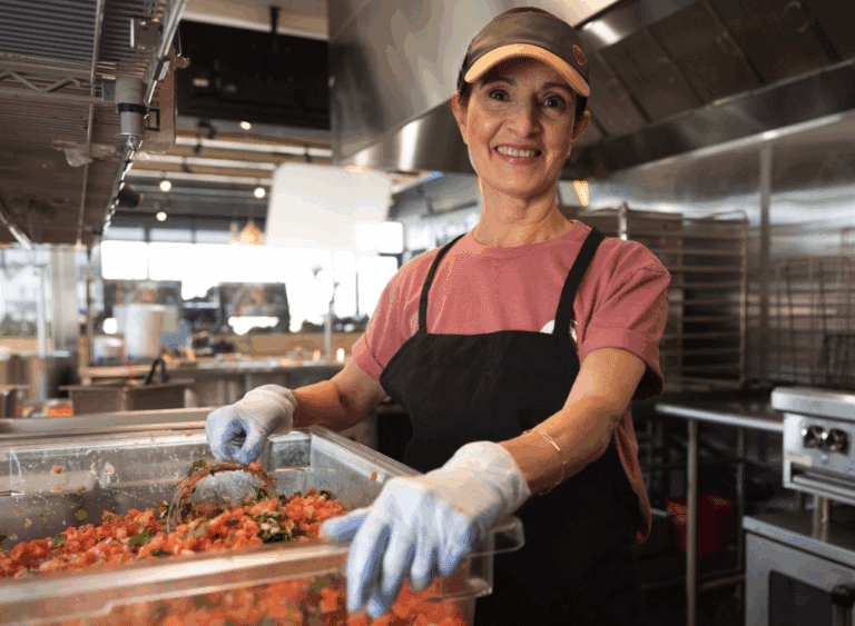Smiling Costa Vida team member preparing fresh salsa inside the restaurant kitchen.