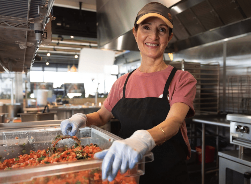 Smiling Costa Vida team member preparing fresh salsa inside the restaurant kitchen.